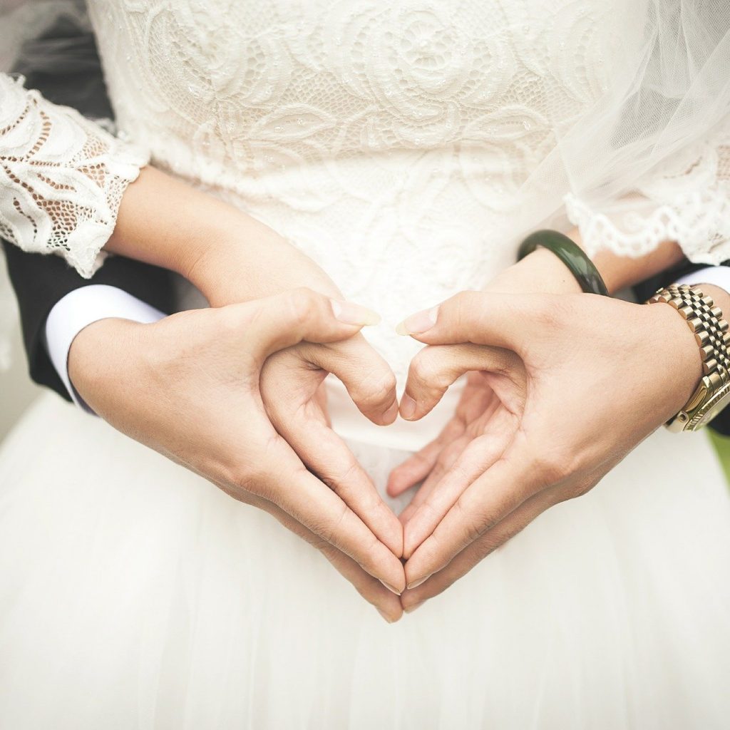 Bride and groom making heart shape with hand