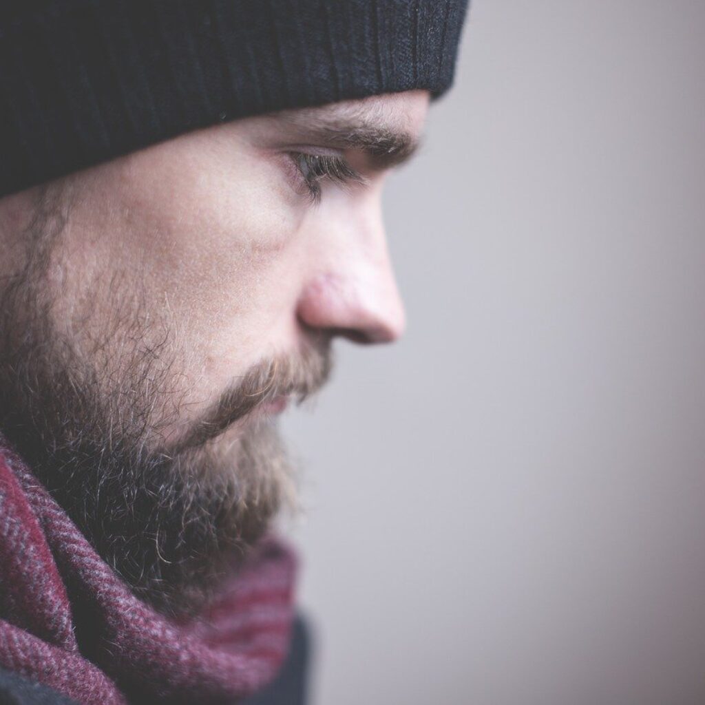 man in coat and hat looking and gazing down