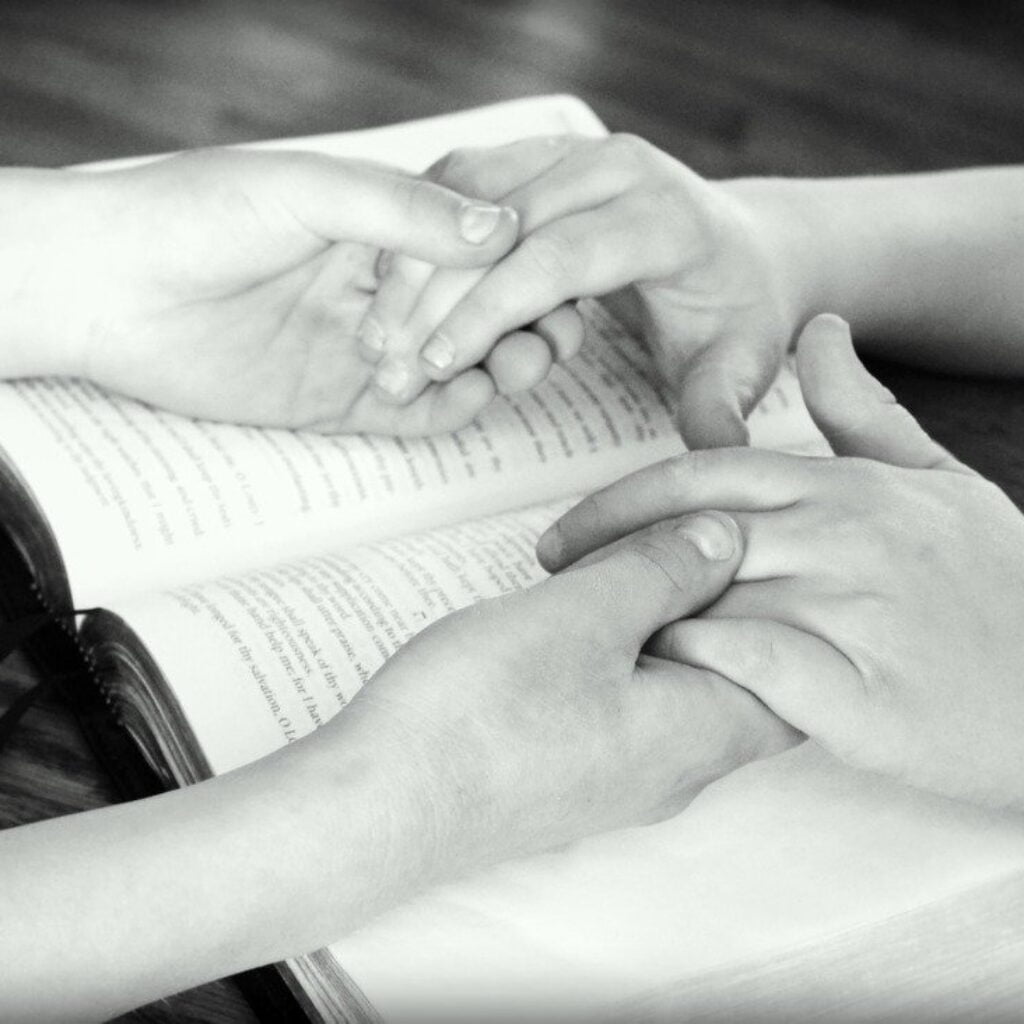 Two people holding hands praying