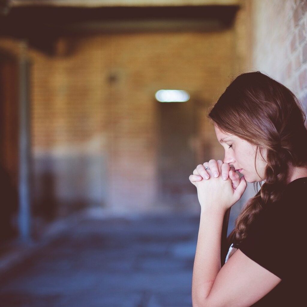 Girl standing by a wall praying