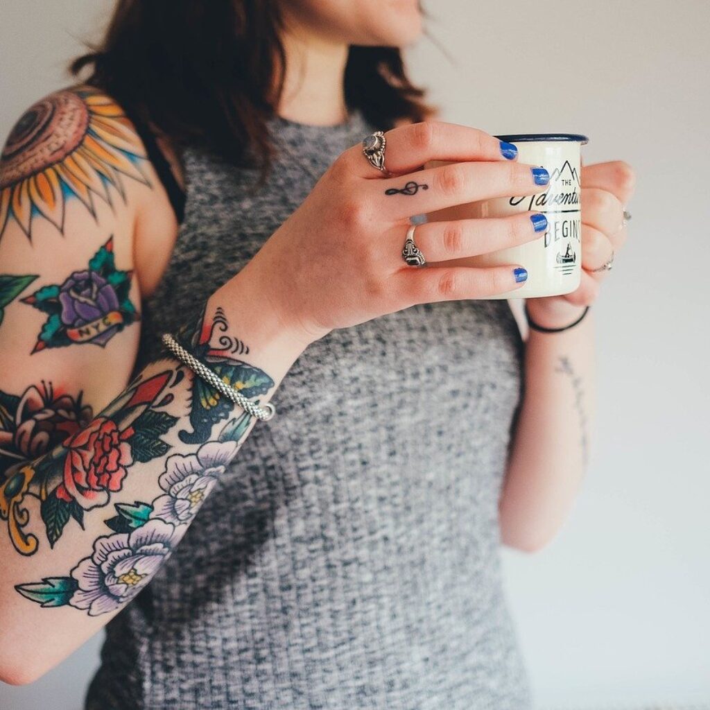 can we go to heaven with tattoos - woman with tattoo drinking from a mug