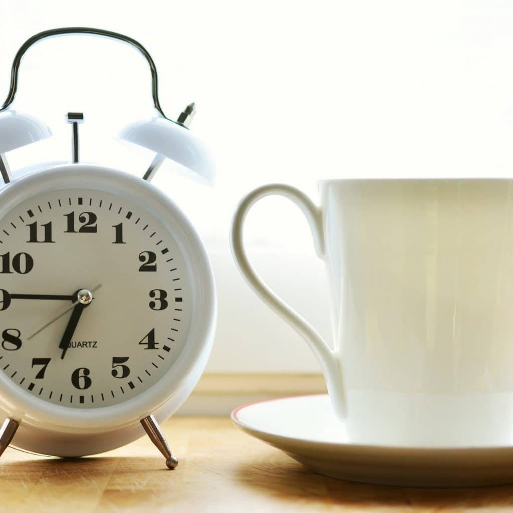 White clock and white tea cup on a table