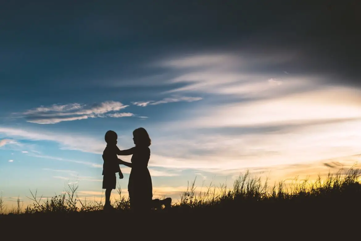 Mother encourage son outside in sunset