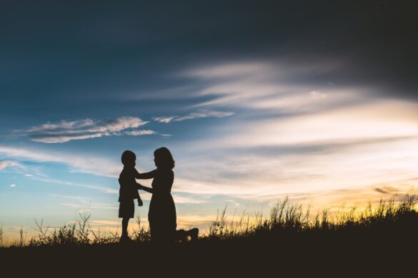 Mother encourage son outside in sunset