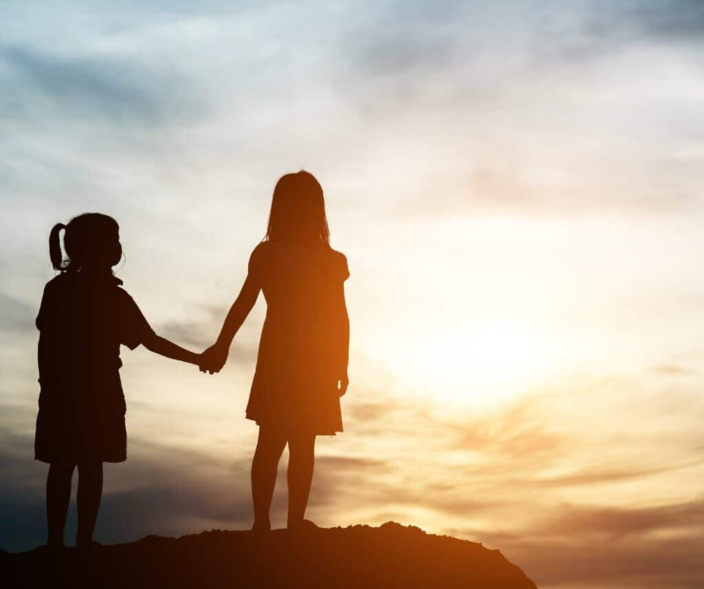 Two girl holding hands on a hill